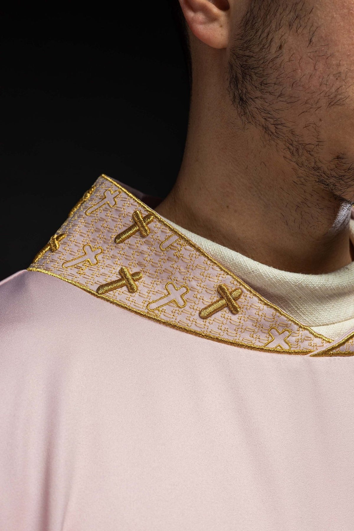 Rose chasuble close-up showing gold embroidery on the collar and cross