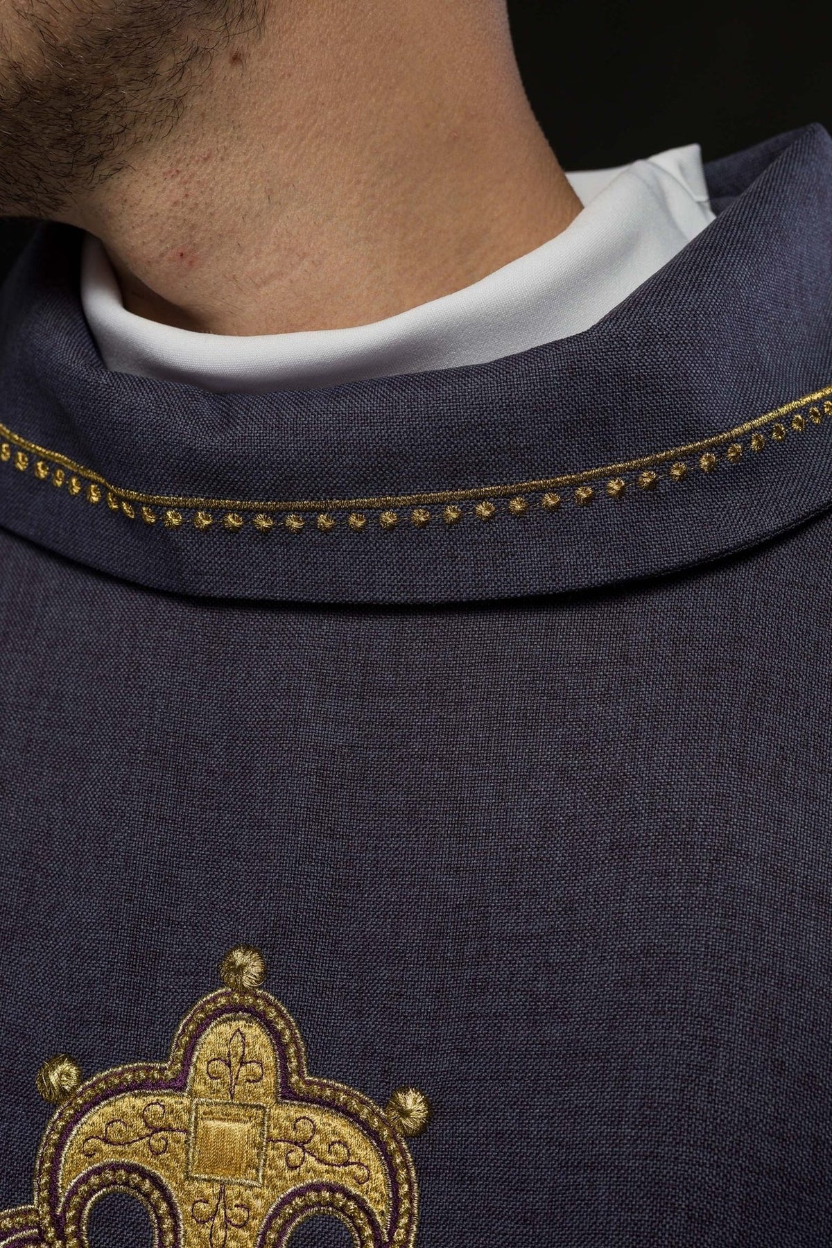 Purple chasuble close-up showing gold collar trim and cross embroidery