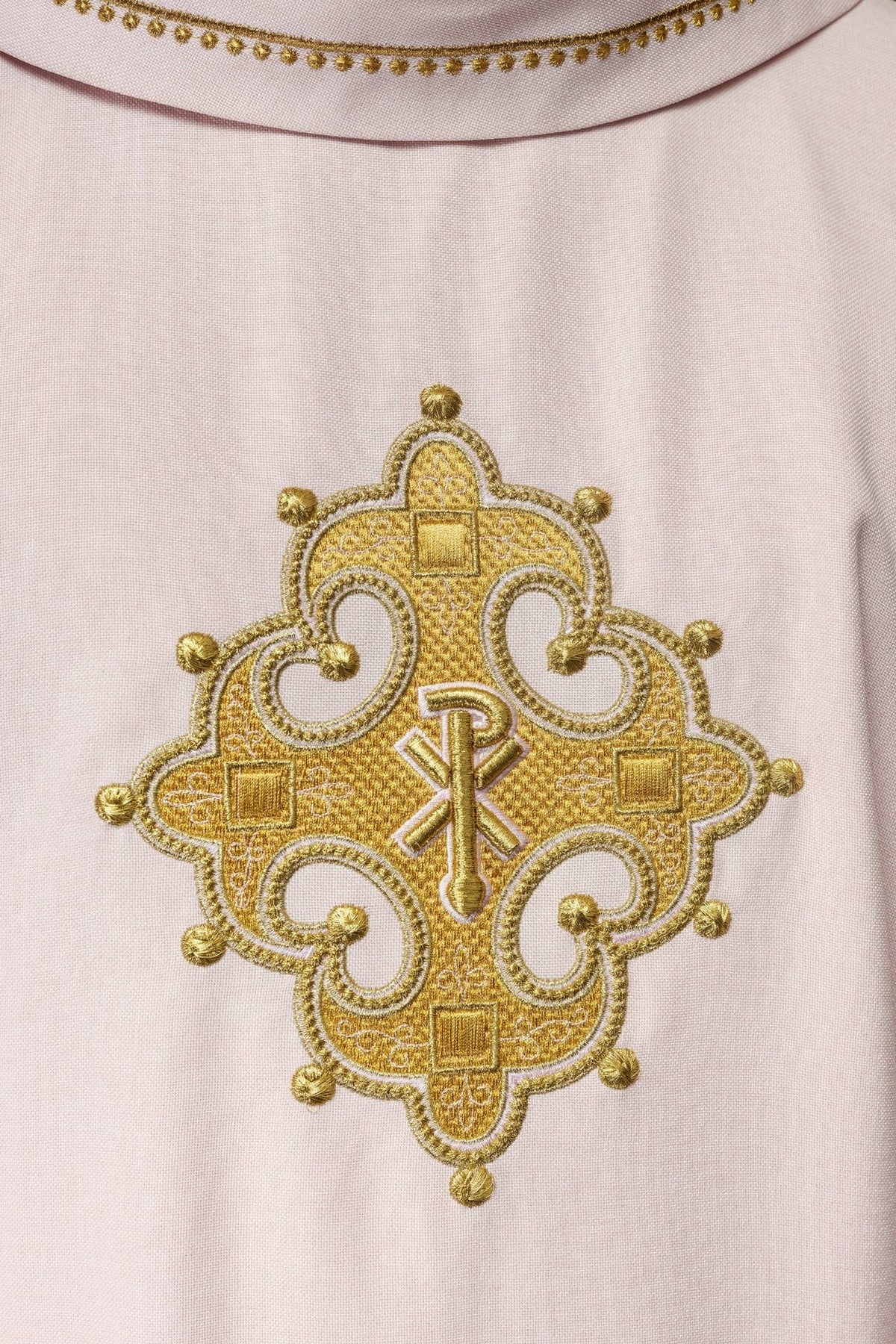 Rose chasuble close-up showing ornate gold cross embroidery