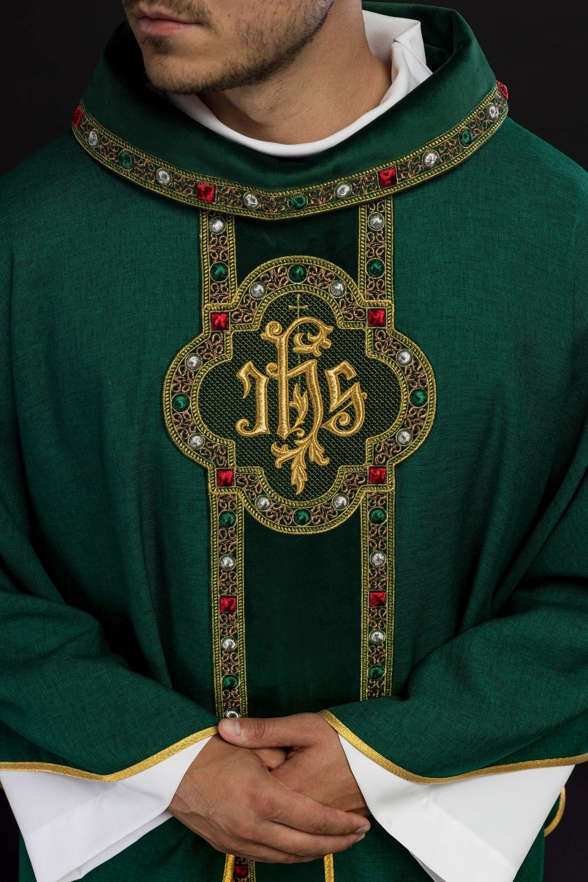 Green chasuble close-up showing IHS embroidery and decorated collar