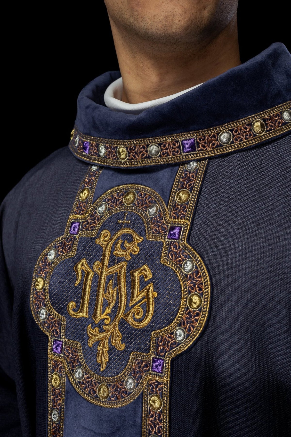 Purple chasuble front close-up showing embroidered IHS emblem and jeweled orphrey