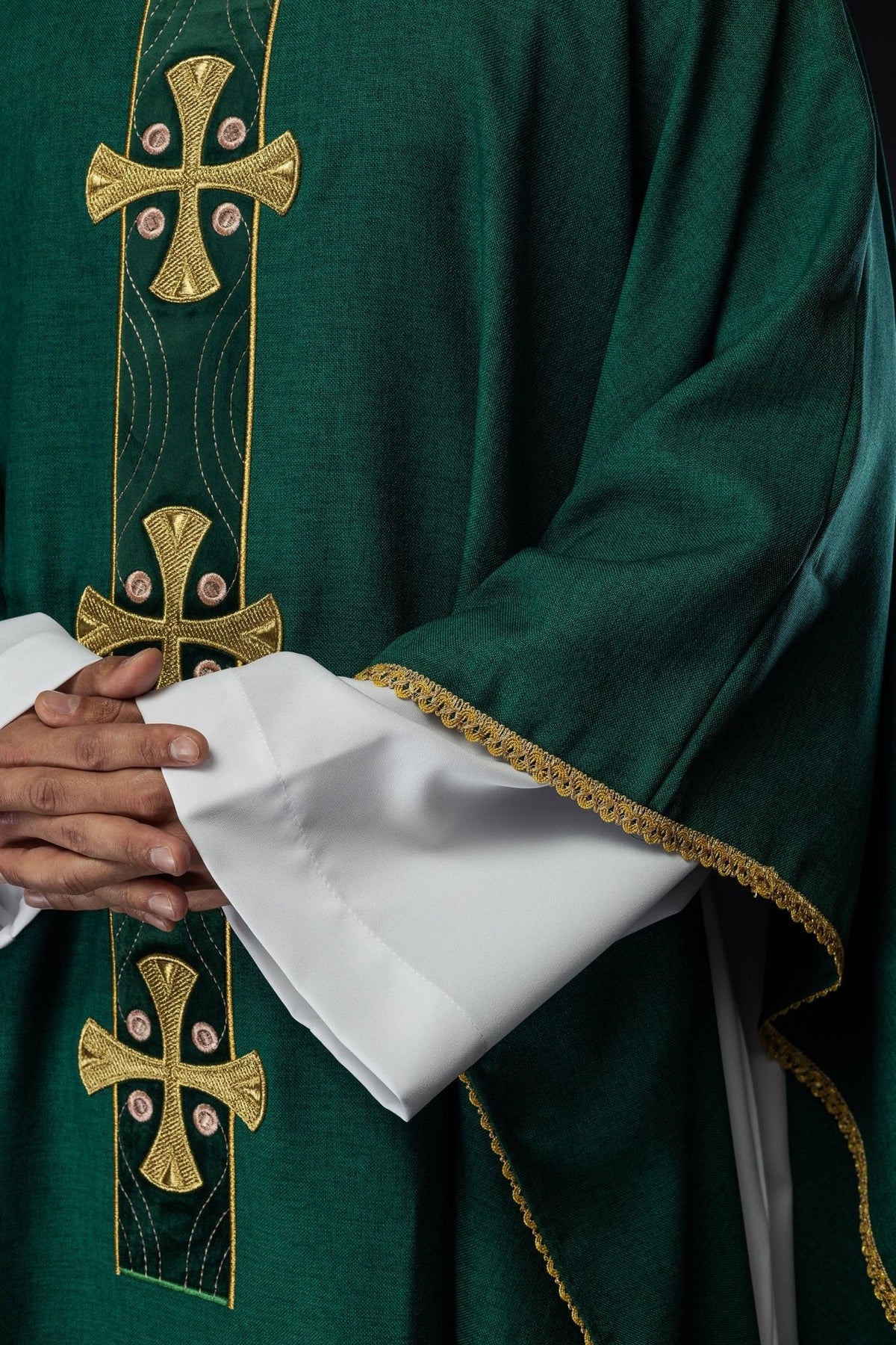 Green chasuble sleeve close-up with gold trim and embroidered cross panel