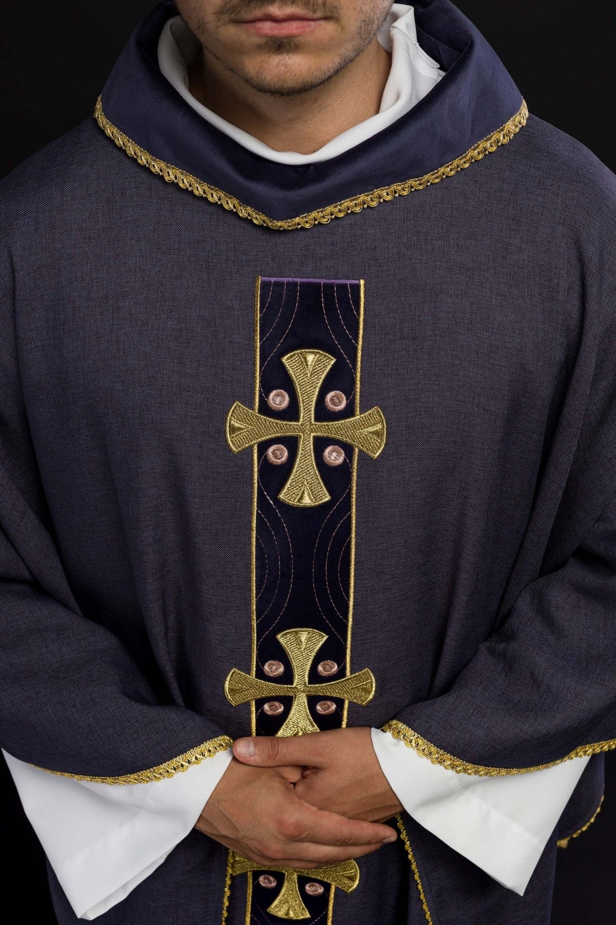 Purple chasuble close-up with embroidered gold crosses and collar trim