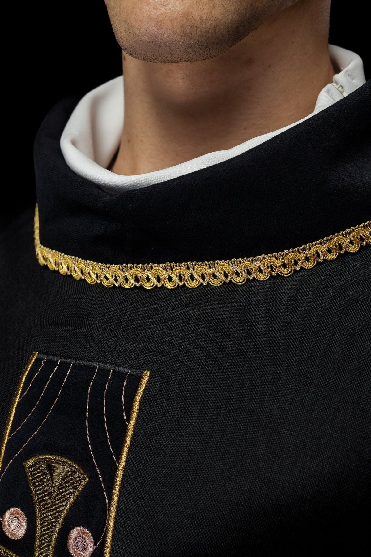 Black chasuble close-up with gold trim and embroidered cross