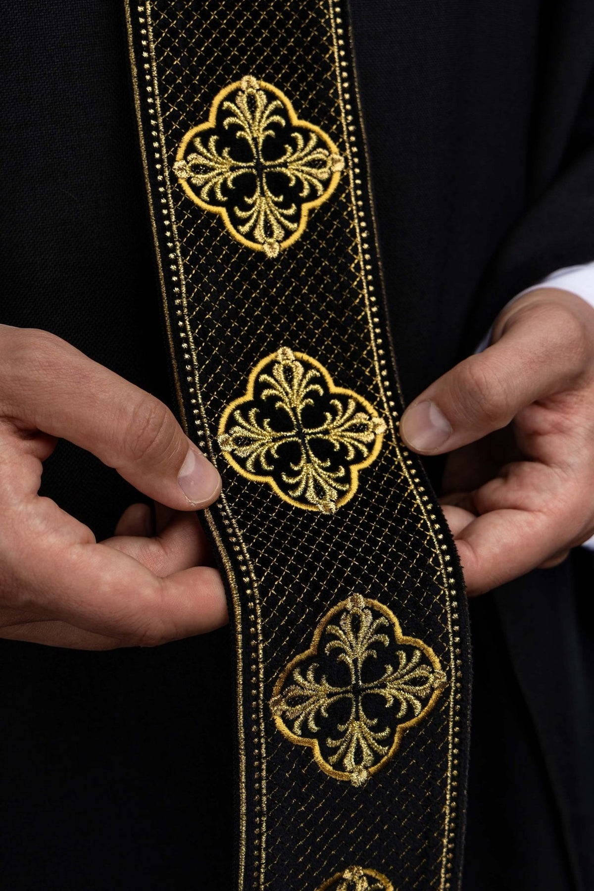 Black chasuble detail showing embroidered gold cross motifs on the orphrey