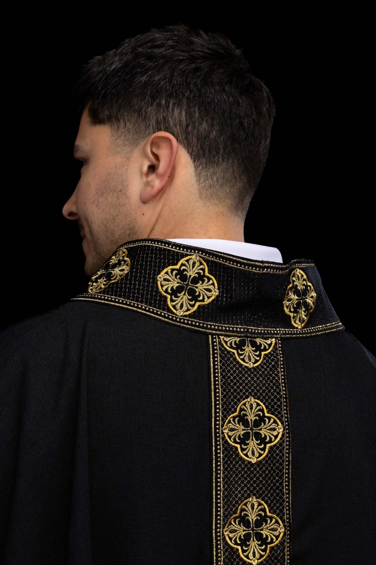 Black chasuble side detail showing plain black fabric and gold-trimmed edge