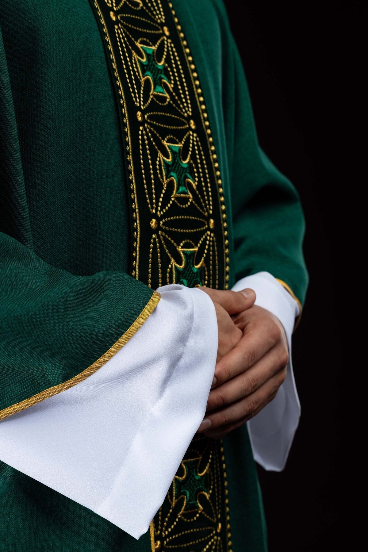Green chasuble side close-up showing embroidered gold trim and cross orphrey