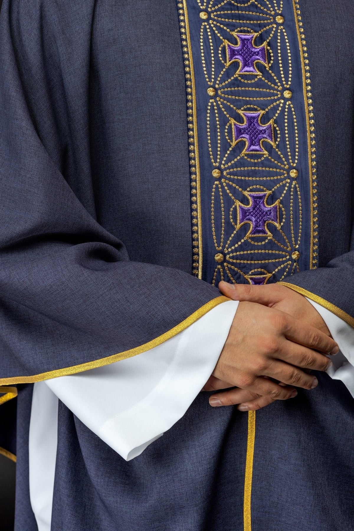 Purple chasuble close-up showing repeated embroidered crosses on the orphrey