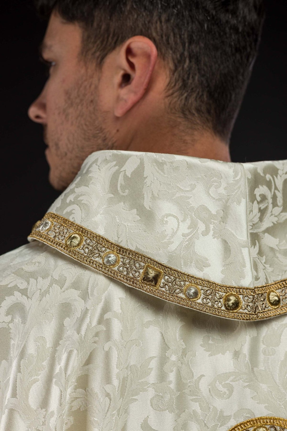 Ecru chasuble close-up showing gold trim and jacquard fabric at the collar
