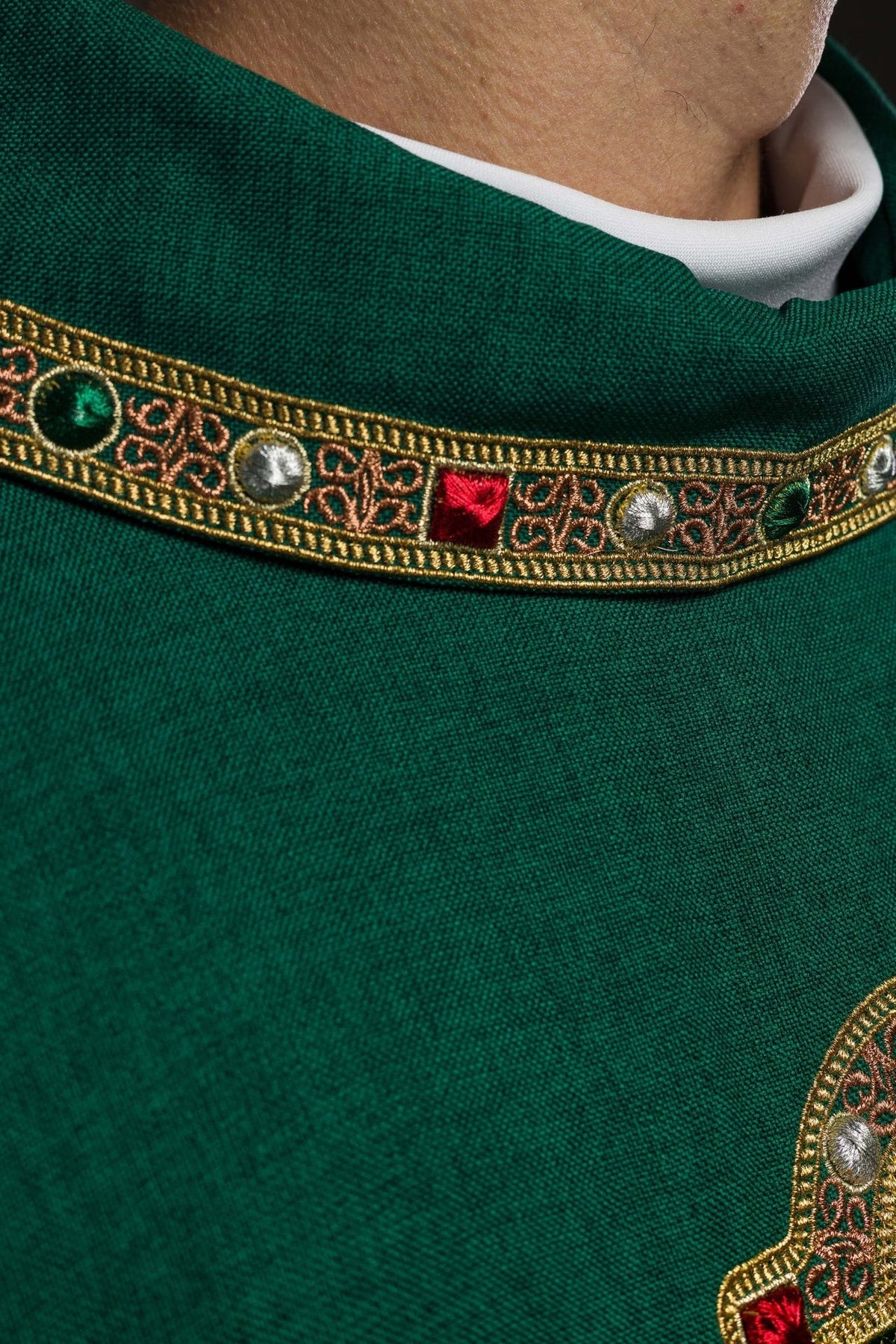 Green chasuble collar trim close-up with ornate gold embroidery and colored accents
