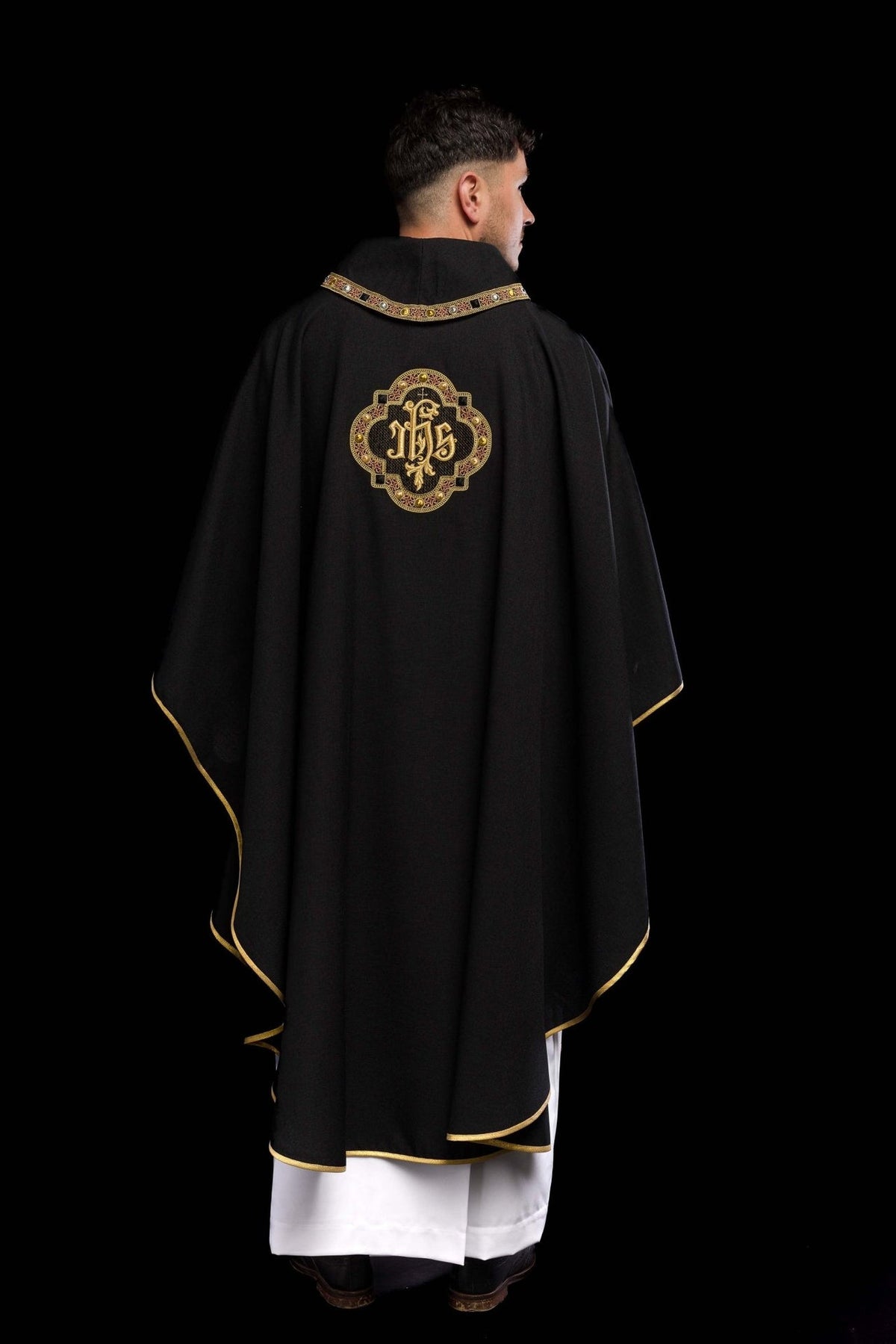 Black chasuble back view with centered IHS embroidery and gold trim