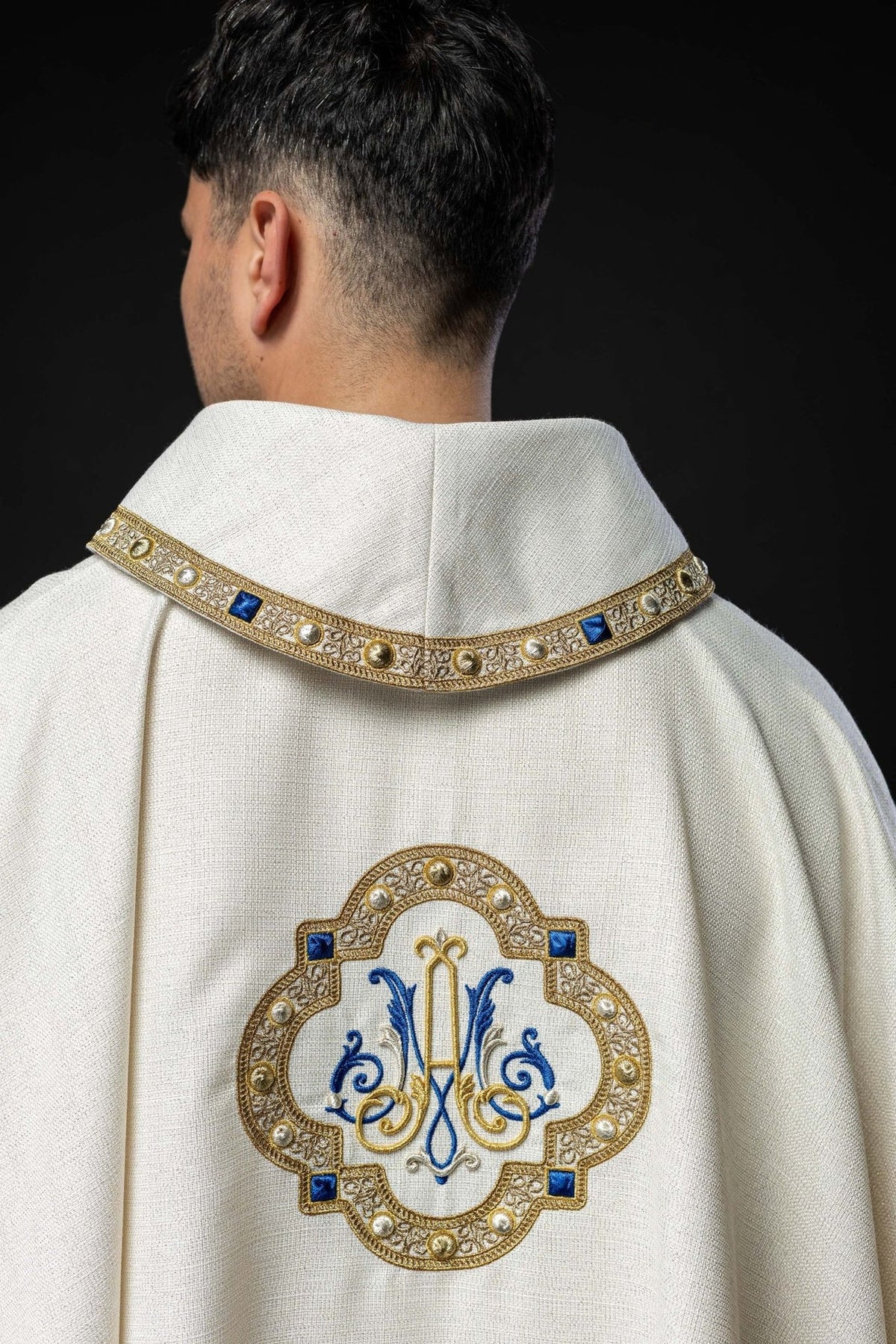 White chasuble back view with embroidered Marian emblem and gold edging