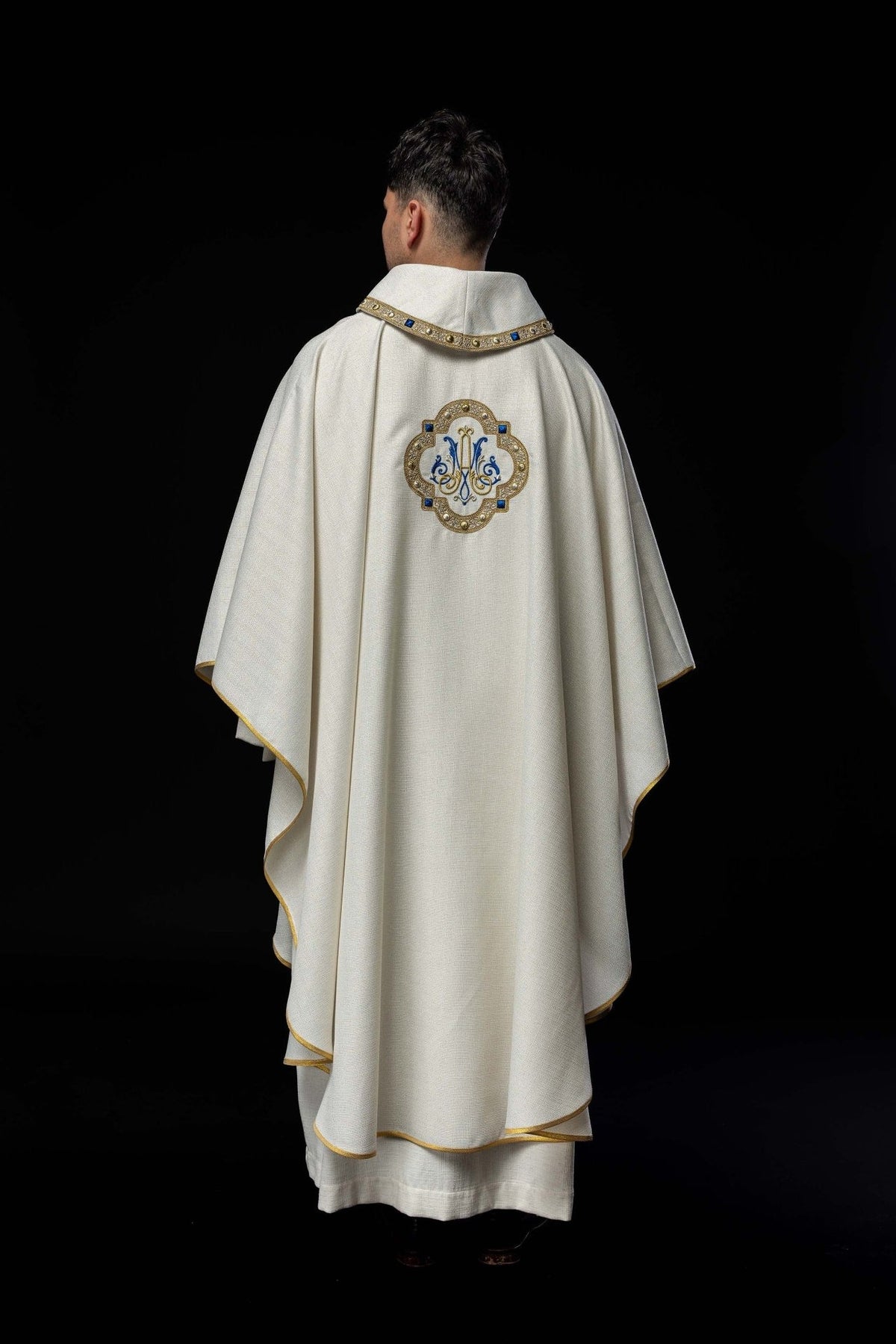 Liturgical chasuble worn from the back, showing the white fabric and gold-trimmed edges