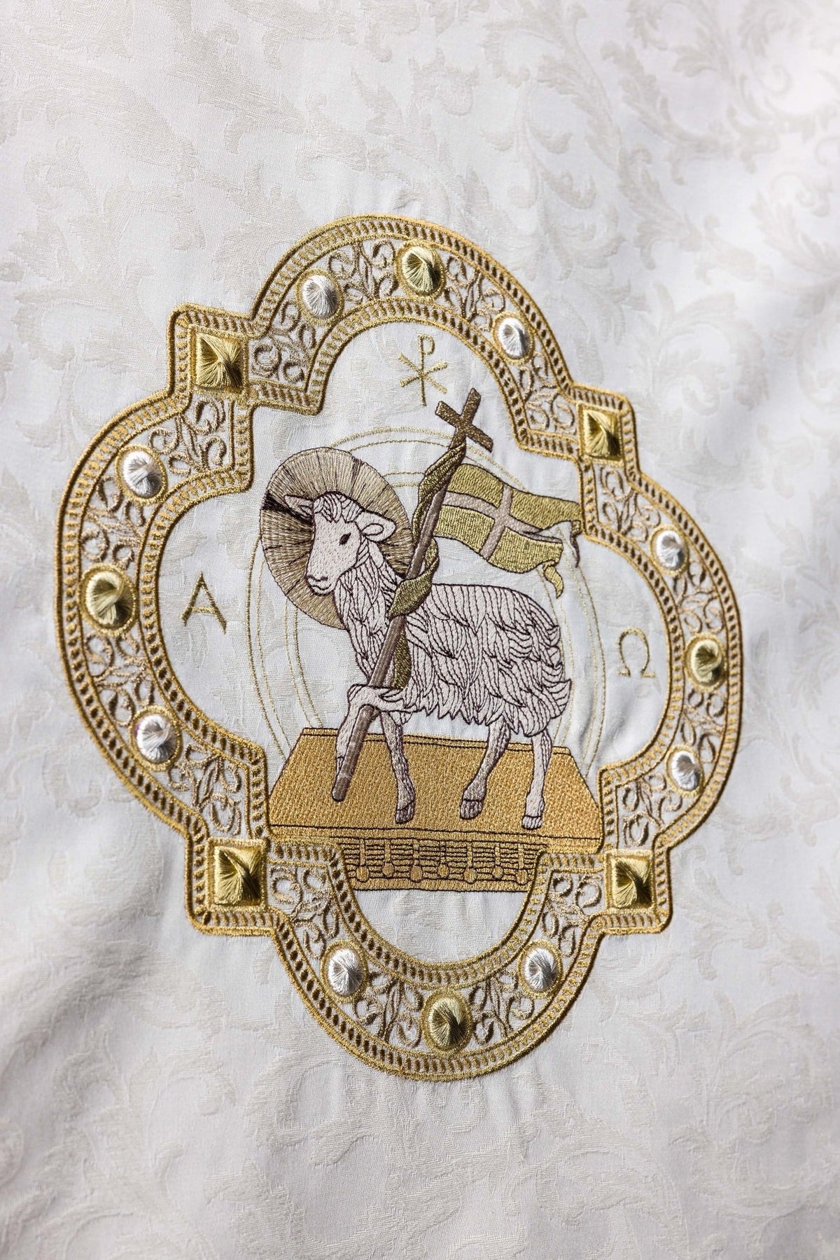 Church lectern cover close-up showing Agnus Dei embroidery in gold and silver