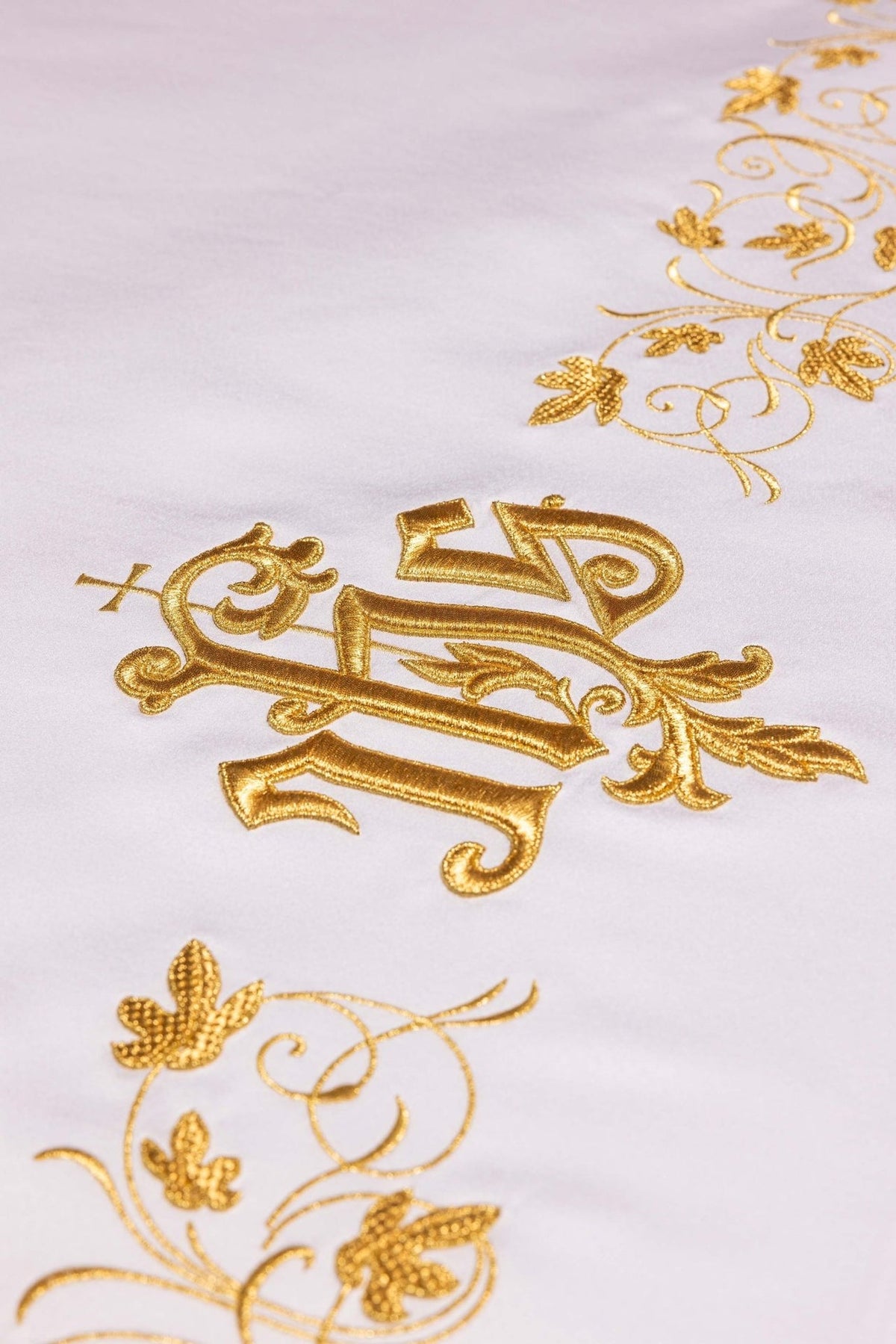 Altar cloth close-up showing gold IHS monogram embroidery on white fabric