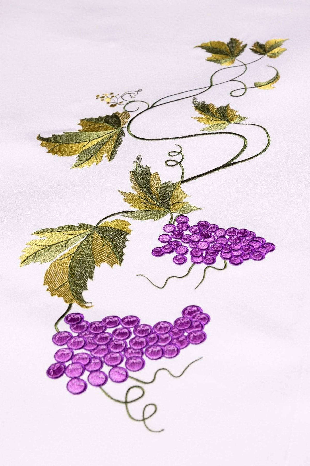 Altar cloth close-up showing embroidered purple grapes with green and gold vine leaves