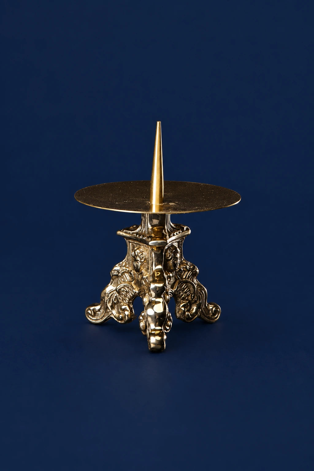 Small brass candlestick with angel motif and round drip plate, front view