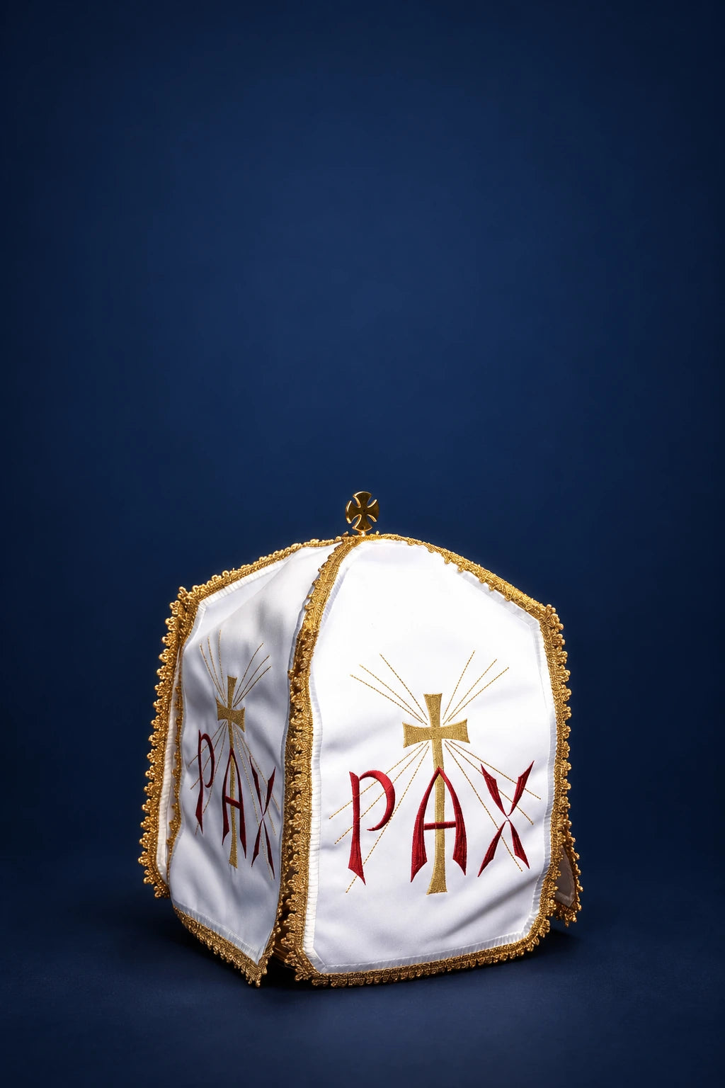 Three-quarter view of a white ciborium veil with gold trim, embroidered PAX, and cross motif