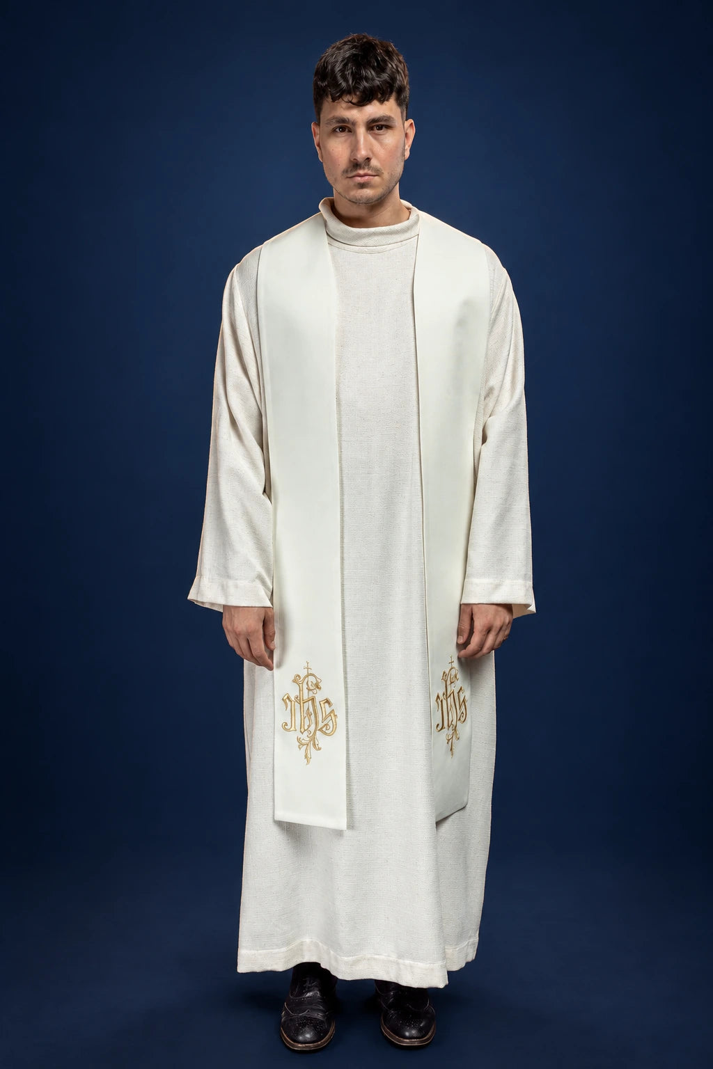 White Catholic stole worn over alb, front view, with gold IHS embroidery near the lower ends