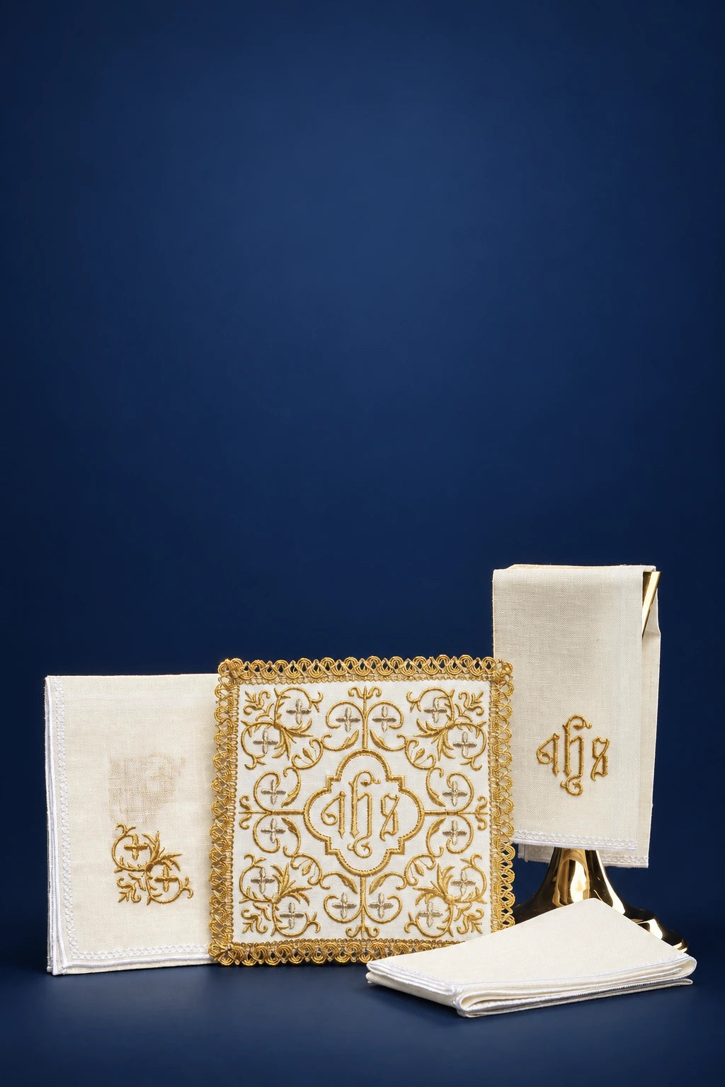 Altar linen set with gold cross and JHS embroidery, including folded cloths and a square corporal with ornate border