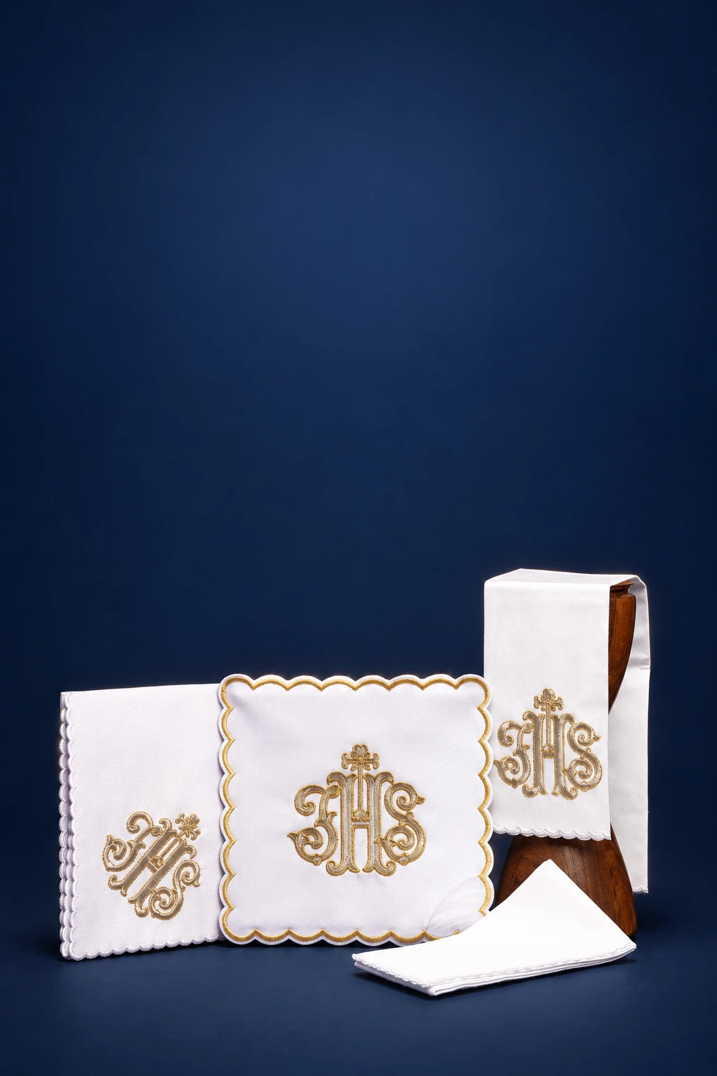 Altar linen set with gold IHS embroidery, including folded corporal, pall, and purificator