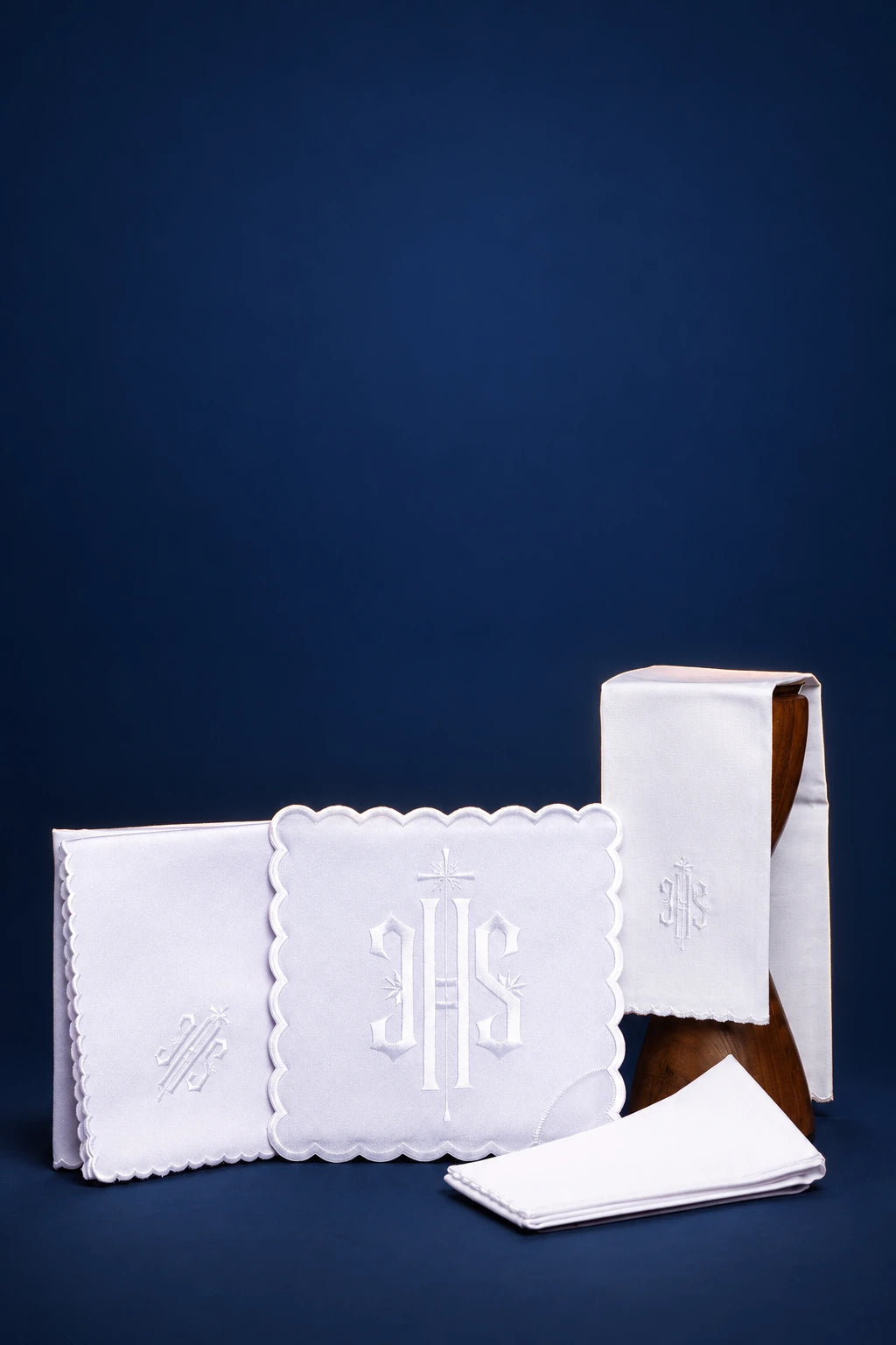 Altar linen set with white scalloped trim and IHS embroidery, shown folded and stacked
