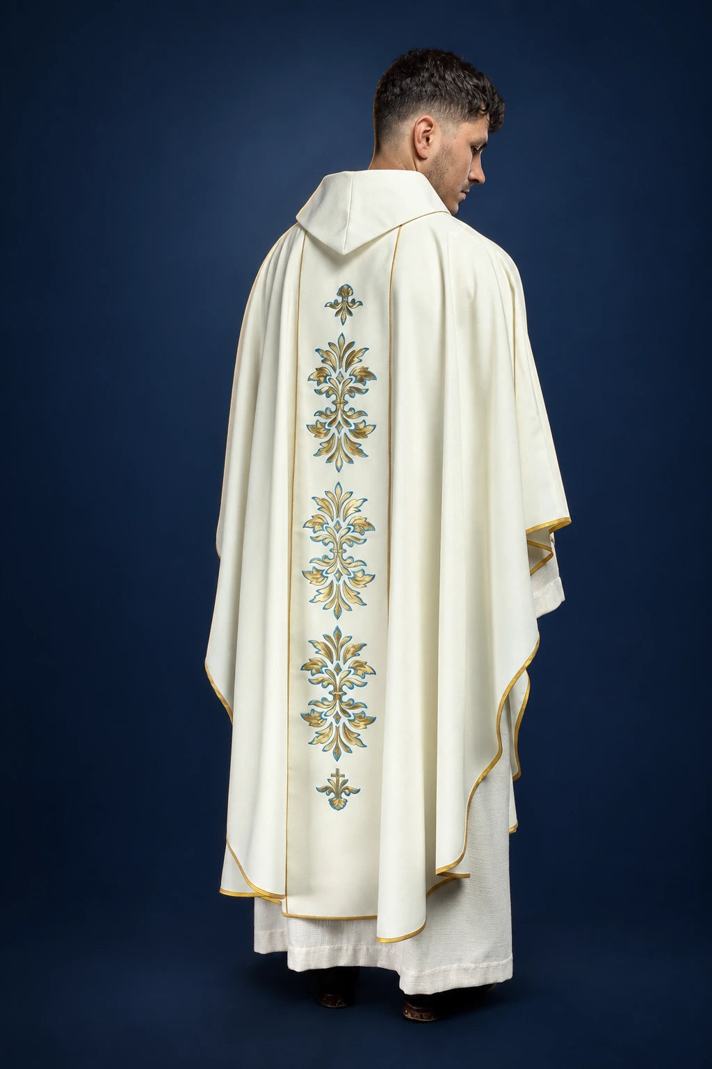Back view of an ecru chasuble with a pointed hooded collar and vertical Marian embroidery down the center panel