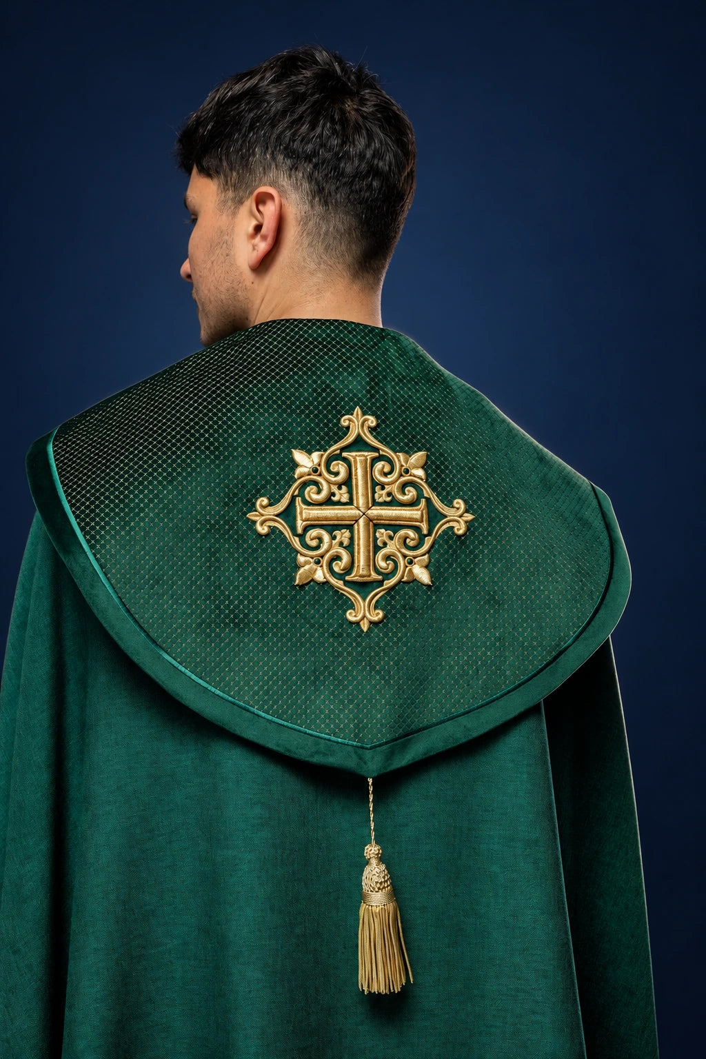 Back view of a green velvet cope with gold embroidered cross and hanging tassel closure