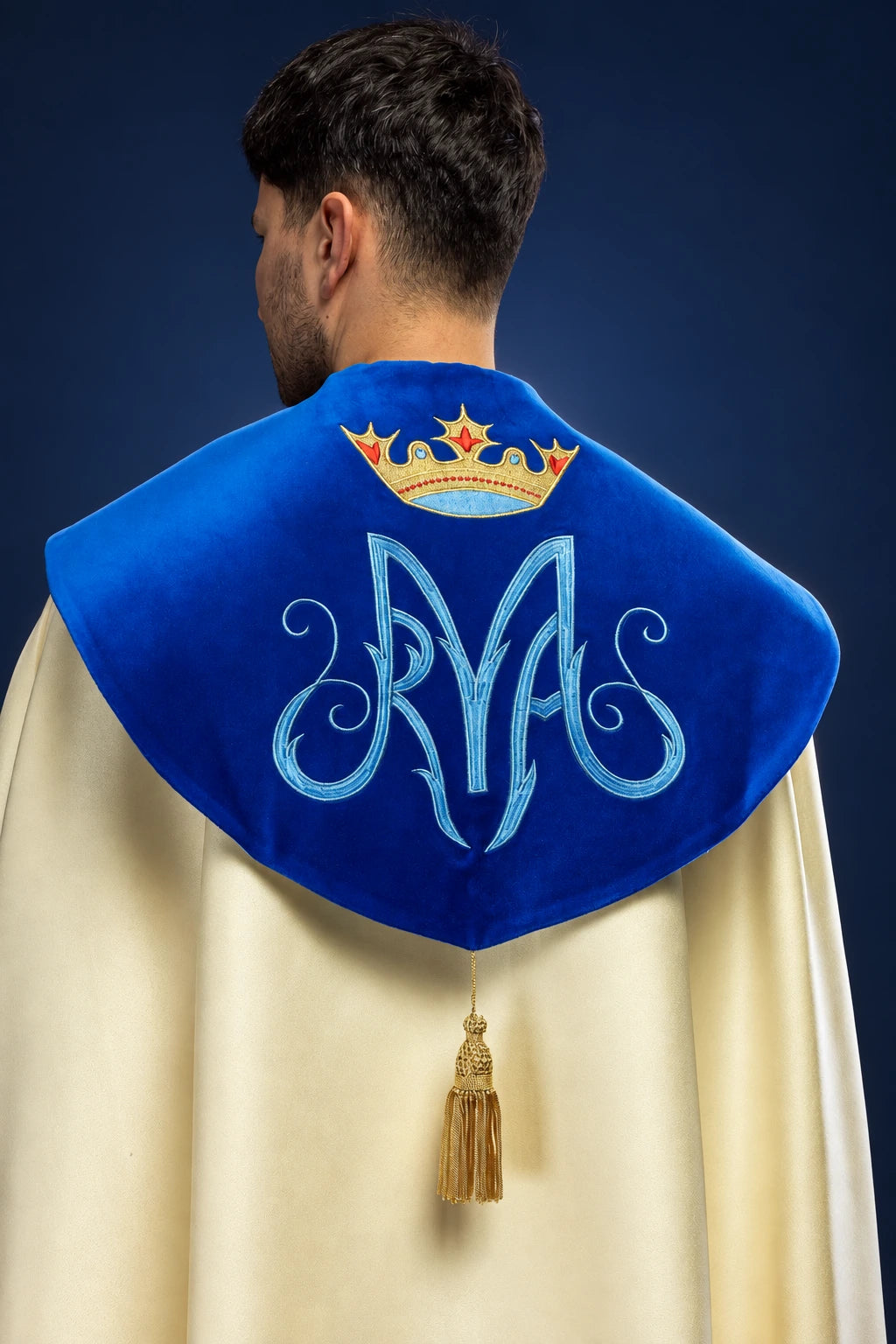 Back view of a Marian cope with blue velvet shoulder cape, embroidered crown and monogram, tassel closure