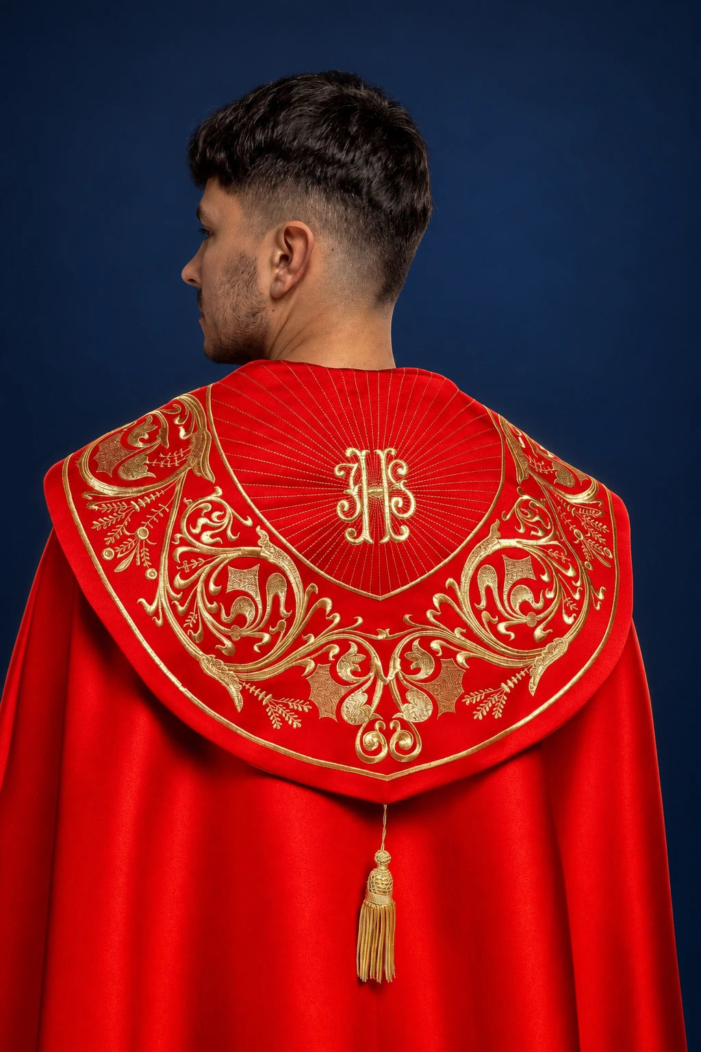 Back view of a red cope with gold IHS embroidery and ornate swirling vine trim