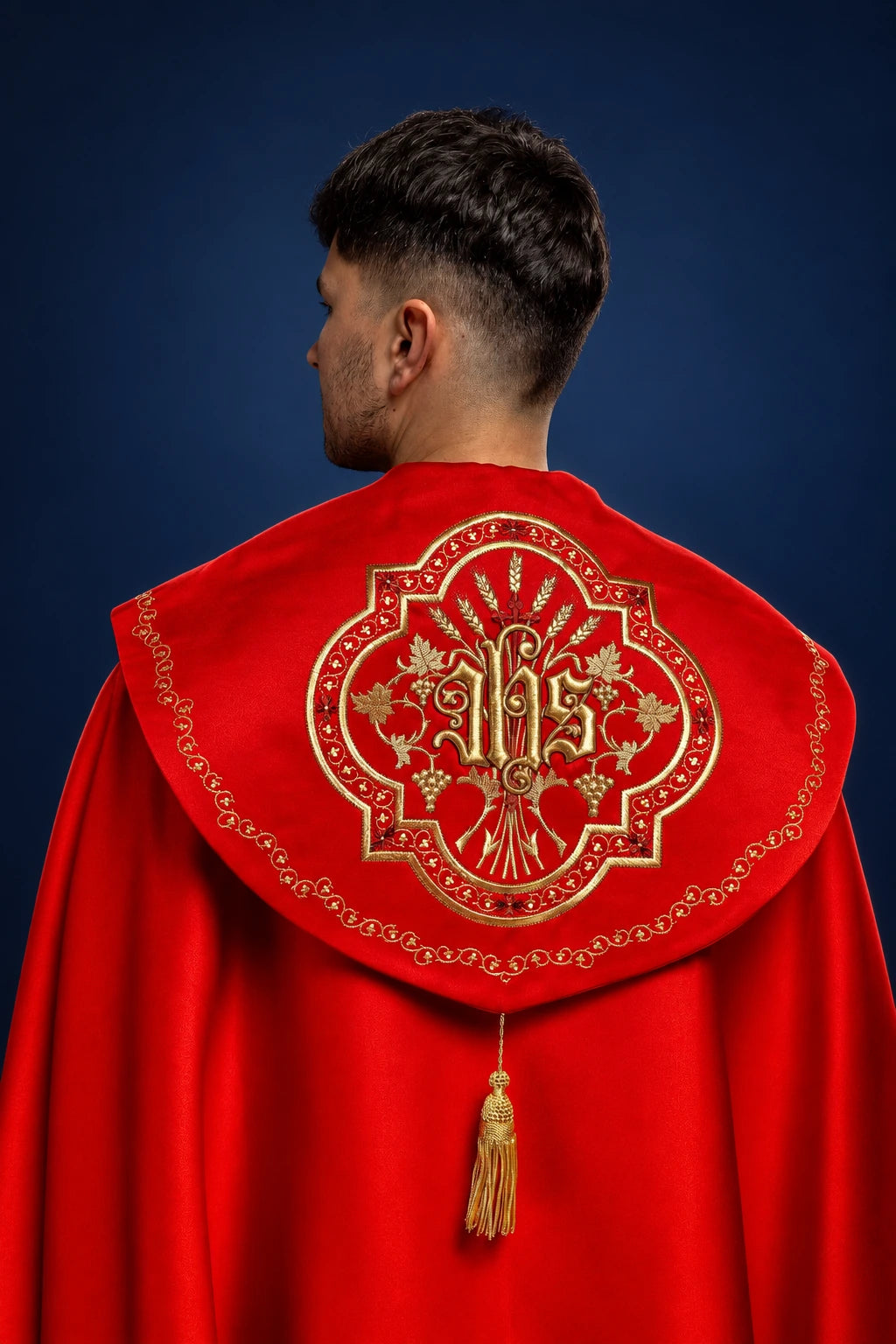 Back view of red cope with gold IHS embroidery and tassel clasp
