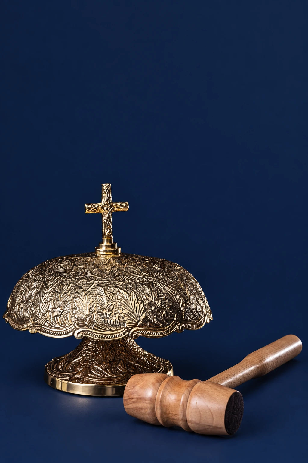 Brass altar bell with ornate engraved dome and wooden mallet beside it