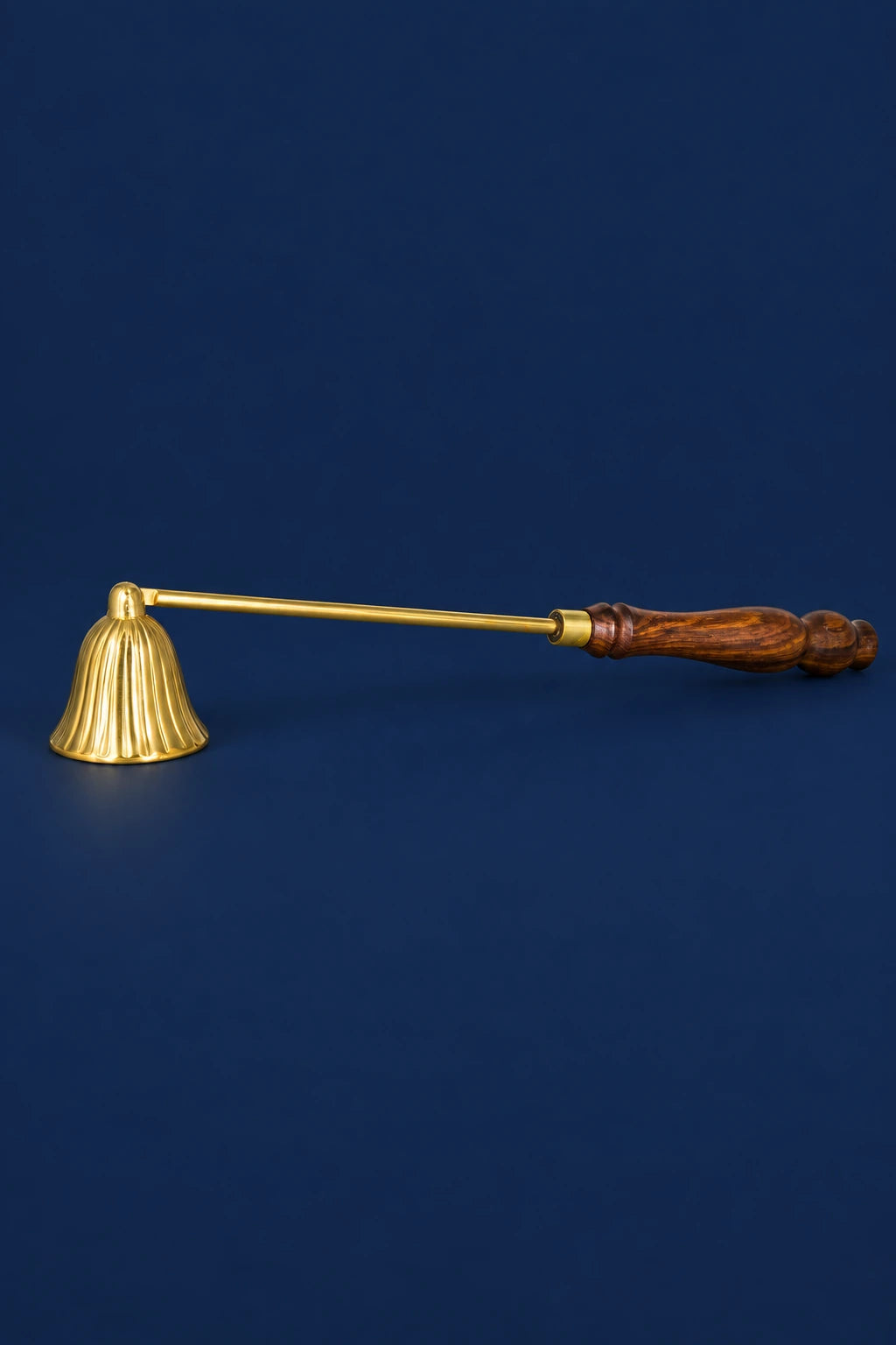 Brass candle snuffer with a fluted bell and carved wooden handle, shown in profile