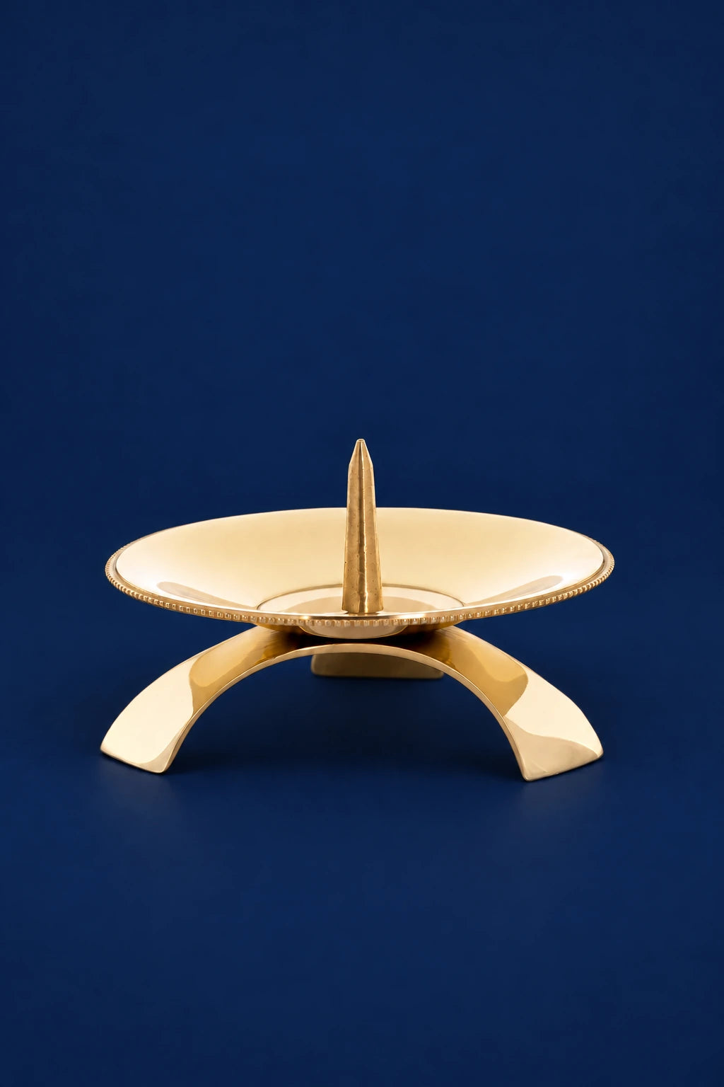 Brass candlestick with shallow dish and pointed center spike, front view