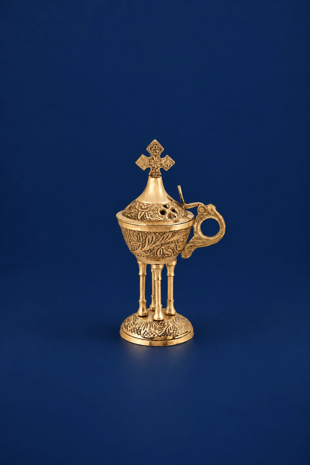Brass censer with cross-topped lid and ornate handle on a pedestal base, front view