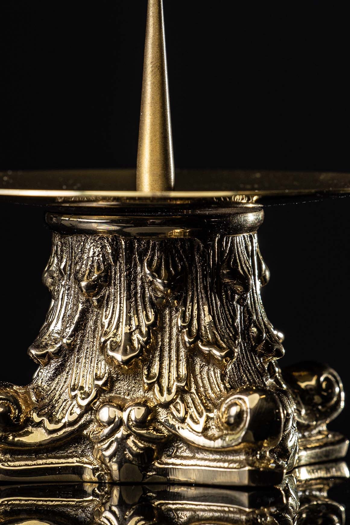 Brass candlestick close-up showing gold ornate scrollwork and textured base
