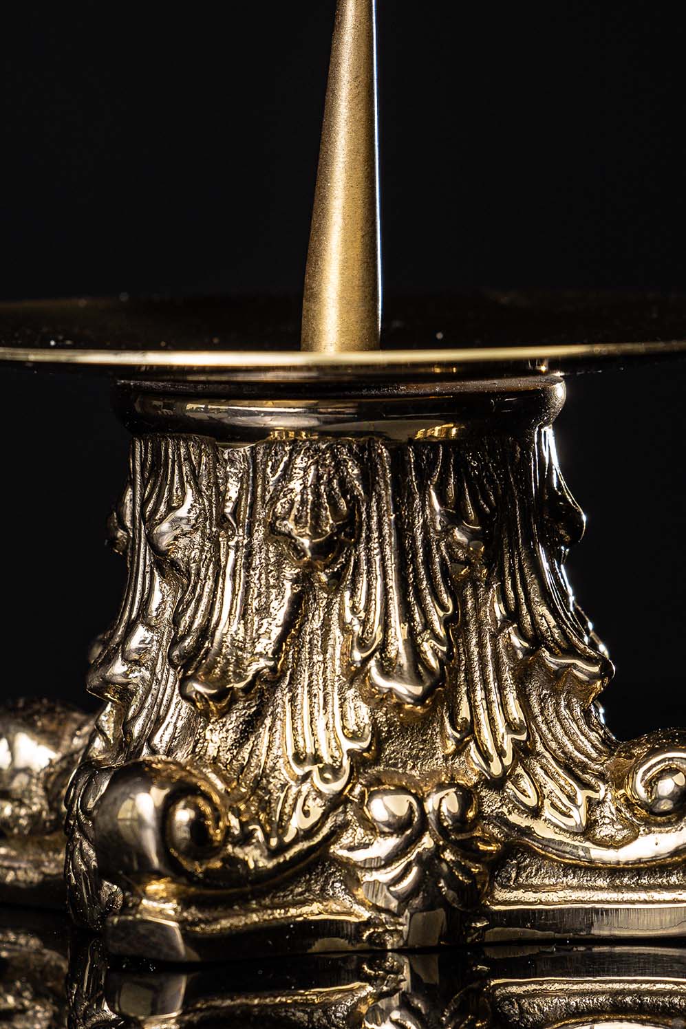 Brass candlestick close-up of gold textured base and decorative scrollwork