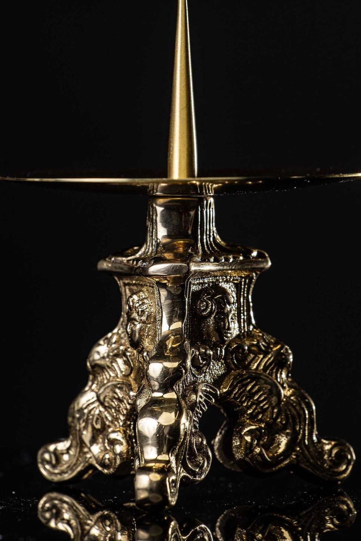 Brass candlestick close-up showing multiple angel motifs and decorative base