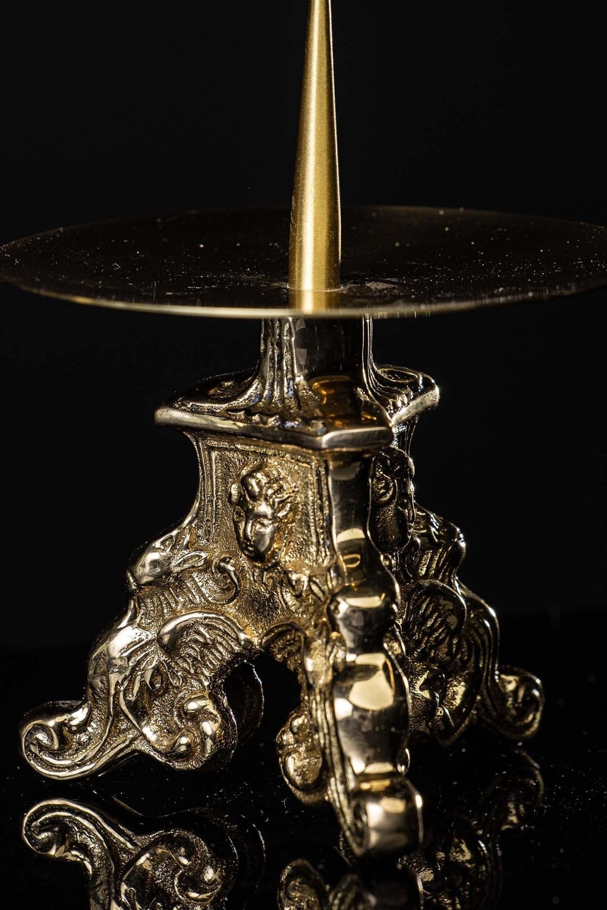 Brass candlestick close-up showing gold candle spike and angel relief