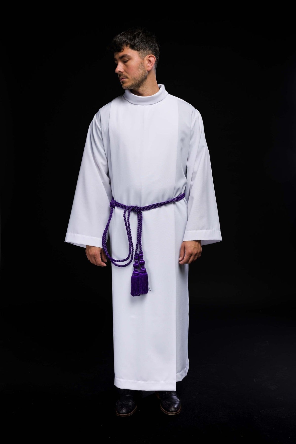 Purple cincture worn around a white alb with hanging braided tassels