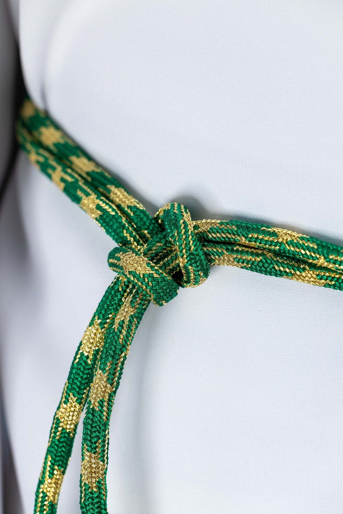 Liturgical cincture close-up showing green and gold woven cord and knotted center