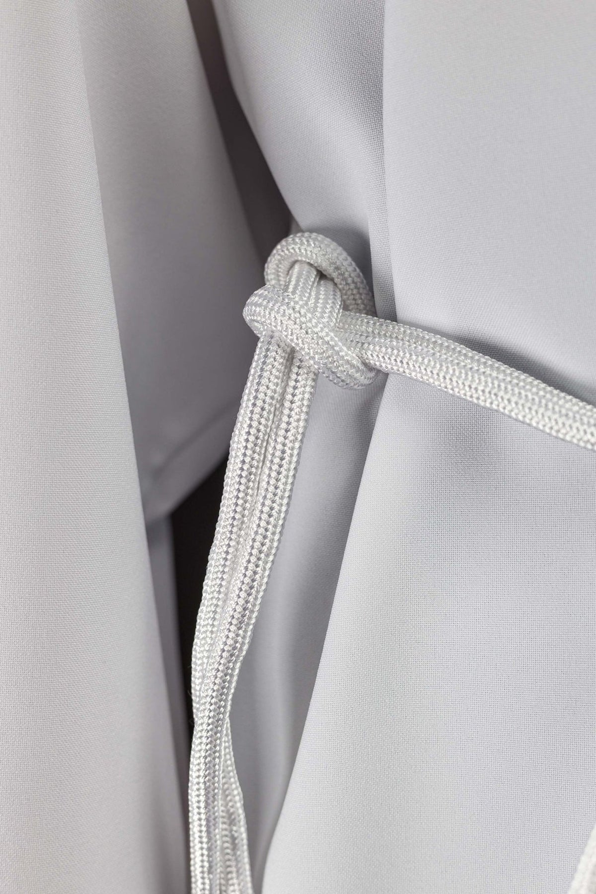 White cincture close-up showing its braided cord and tied knot