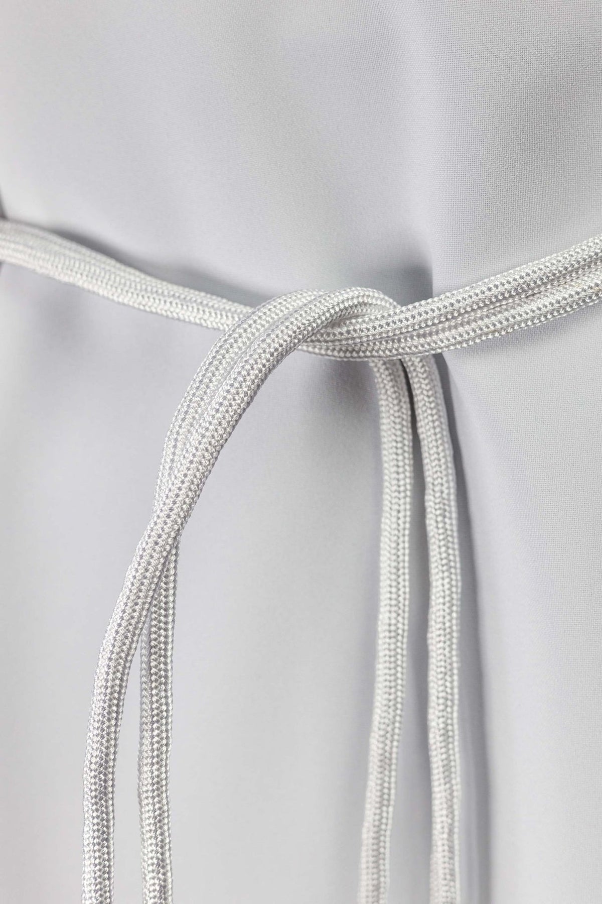 White cincture close-up showing its braided cord loop and knot