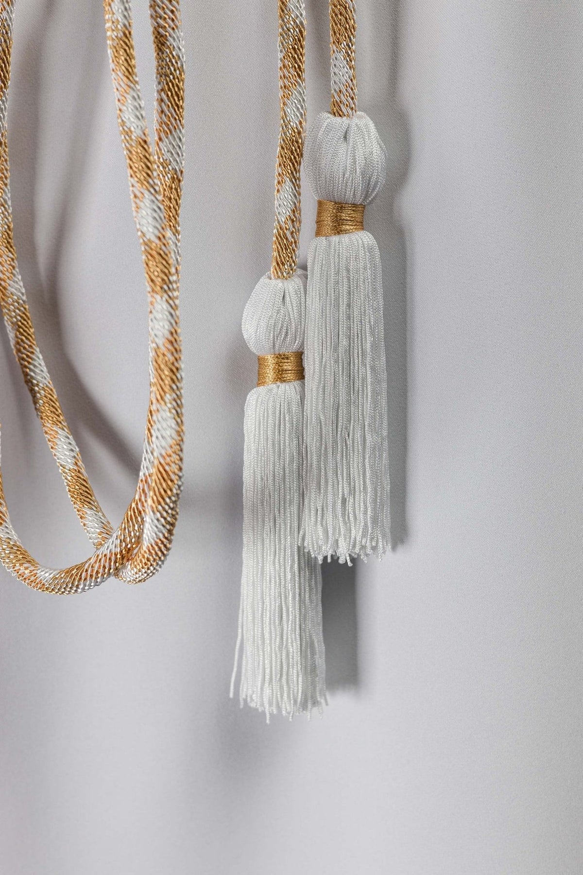 White and gold cincture detail showing white tassels with gold bands