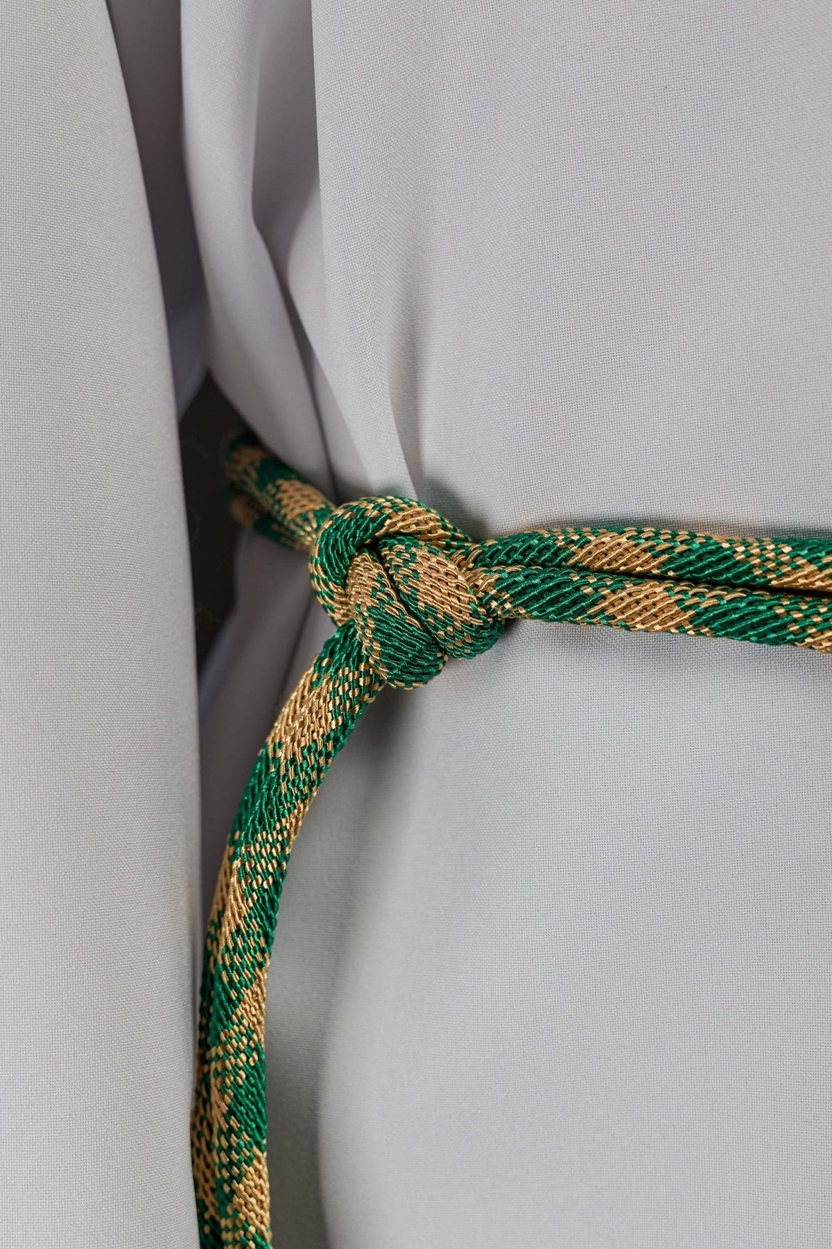 Green and gold cincture close-up showing the braided cord and tied knot