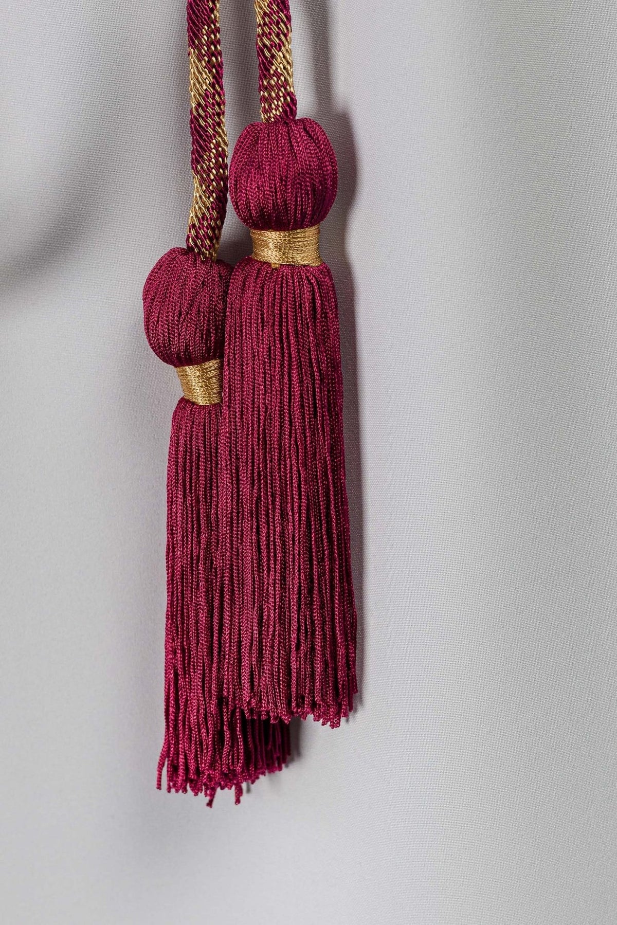 Red-and-gold cincture close-up of paired red tassels with gold bands