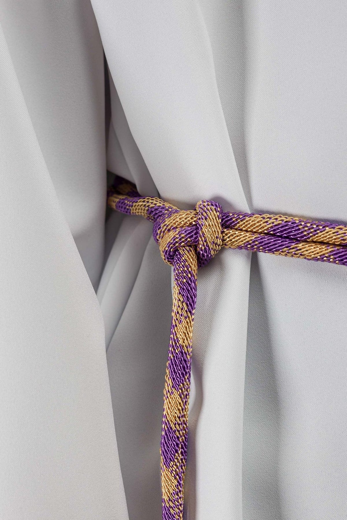 Purple and gold cincture close-up showing the braided cord and tied knot