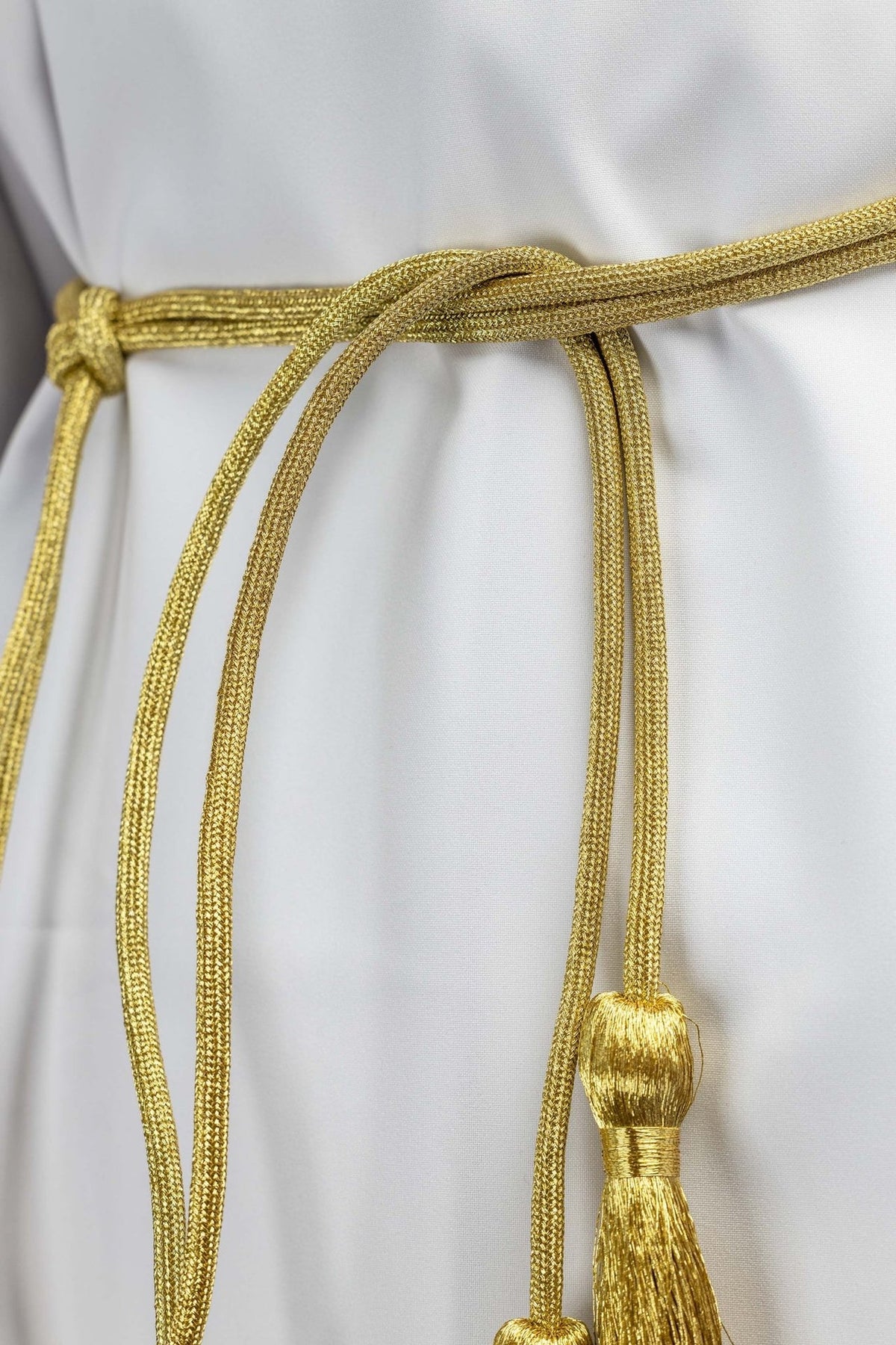 Gold cincture close-up showing braided cord, knot and tassel tops