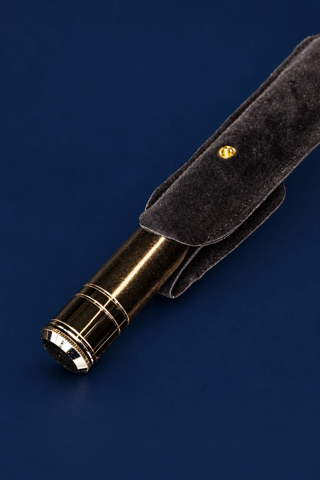 Close-up of a metal aspergillum in a dark velvet case, showing the handle and metal sprinkler end