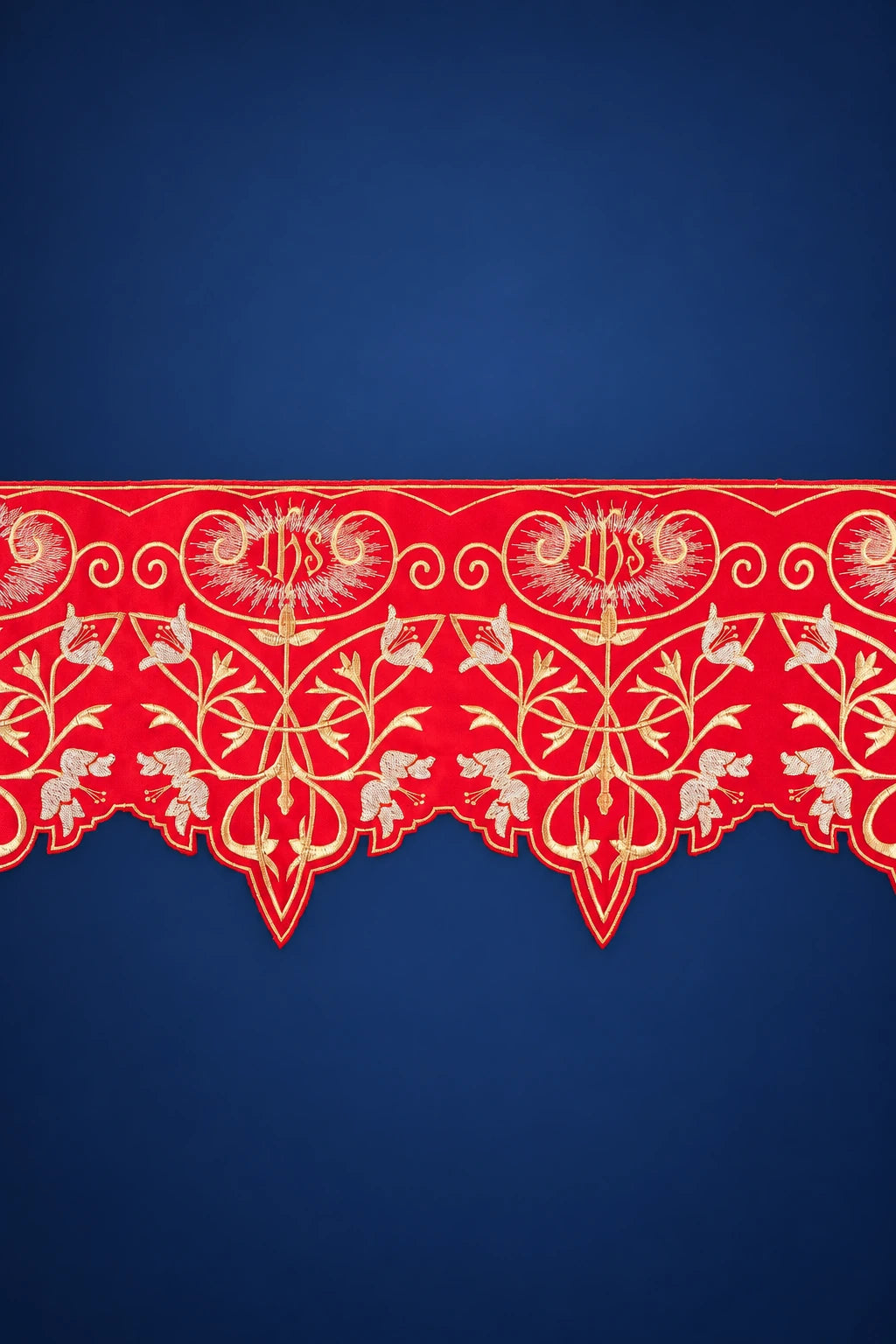Close-up of red altar lace with gold IHS monograms and vine pattern, scalloped border